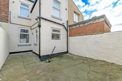 a white building with a fence and a brick wall at Scott House - Air Host & Stay - Parking - Contractor friendly in Liverpool
