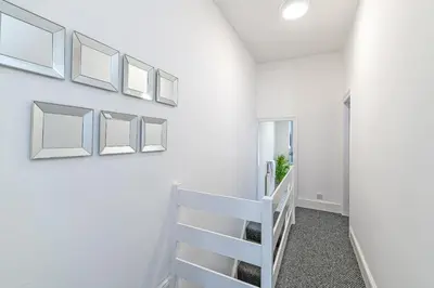 a white staircase in a white room with pictures on the wall at Scott House - Air Host & Stay - Parking - Contractor friendly in Liverpool