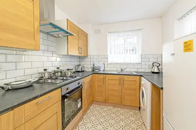 a kitchen with wooden cabinets and a sink and a refrigerator at Scott House - Air Host & Stay - Parking - Contractor friendly in Liverpool