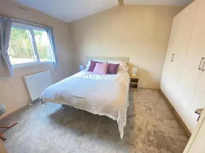 a bedroom with a large white bed with pink pillows at Angella's Caravan - Morecambe in Morecambe