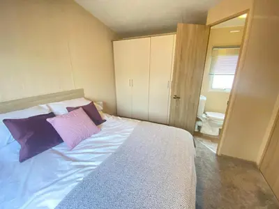 a bedroom with a large bed with purple pillows at Angella's Caravan - Morecambe in Morecambe