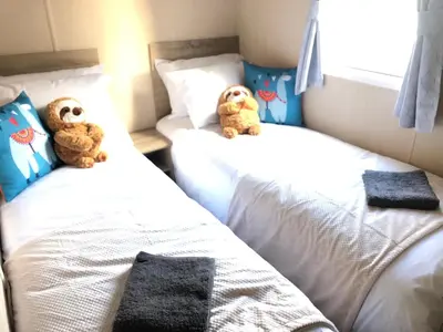 two teddy bears sitting on two beds in a bedroom at Angella's Caravan - Morecambe in Morecambe