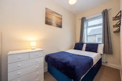 a bedroom with a bed and a dresser and a window at James Street Terrace Great Harwood in Great Harwood
