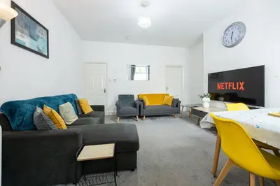 a living room with couches and a clock on the wall at James Street Terrace Great Harwood in Great Harwood