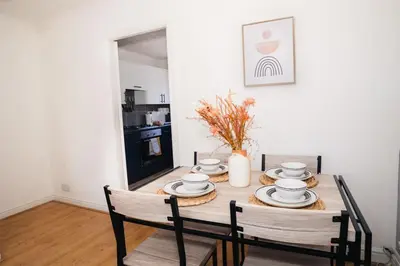 a dining room table with chairs and a vase on it at Haydock Cozy 2-Bedroom Home with Free Parking in Haydock