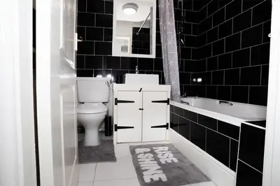 a black tiled bathroom with a toilet and a sink at Haydock Cozy 2-Bedroom Home with Free Parking in Haydock