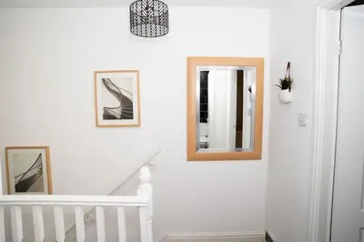 a white staircase with a mirror and pictures on the wall at Haydock Cozy 2-Bedroom Home with Free Parking in Haydock