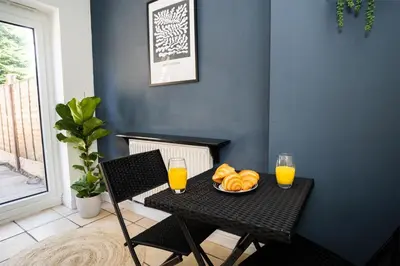 a table with a plate of bread and two glasses of orange juice at Haydock Cozy 2-Bedroom Home with Free Parking in Haydock