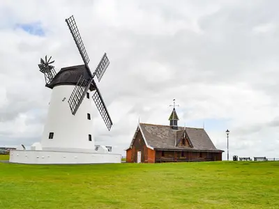 a windmill in a field next to a building at Commonside Cottage in Lytham St Annes