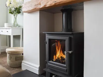 a stove in a living room with a fireplace at Commonside Cottage in Lytham St Annes