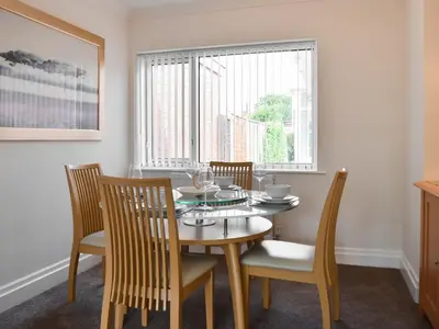 a dining room with a table and chairs and a window at Commonside Cottage in Lytham St Annes
