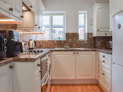 a kitchen with white cabinets and a sink at Commonside Cottage in Lytham St Annes