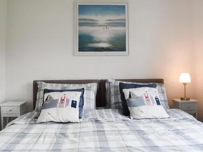 a bed with blue and white checked sheets and pillows at Commonside Cottage in Lytham St Annes