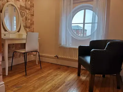 a living room with a chair and a mirror at Spacious house Liverpool city centre L1, sleeps 16 in Liverpool