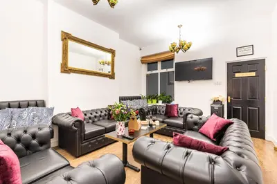 a living room with black leather couches and pink pillows at Christian Retreat Holiday Let in Blackpool