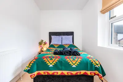 a bedroom with a bed with a green comforter at Christian Retreat Holiday Let in Blackpool