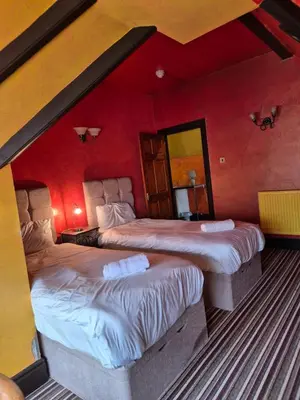 two beds in a room with red walls at Fifteens of Swinley in Wigan