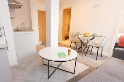 a small living room with a table and a kitchen at Boutique 1BR Apartment in the heart of Preston in Preston