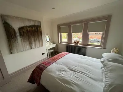 a bedroom with a bed and a table and windows at Cosy hideaway in leafy Lytham in Lytham St Annes