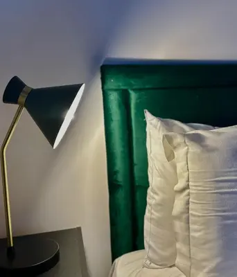 a bed with a green headboard and a lamp and a pillow at The Hideaway by Boutique 56 in Liverpool