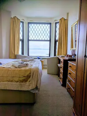 a bedroom with a bed and a desk and windows at Craigwell in Morecambe