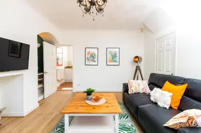 a living room with a black couch and a table at Stylish Comfort: 2BR Home in the Heart of Wigan in Pemberton