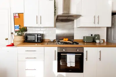 a kitchen with white cabinets and a stove top oven at Stylish Comfort: 2BR Home in the Heart of Wigan in Pemberton