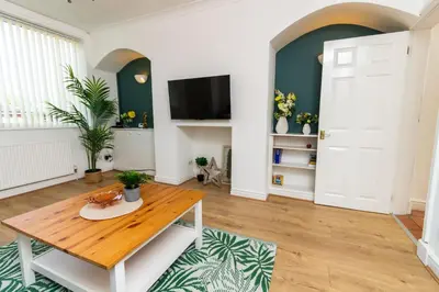 a living room with a table and a tv at Stylish Comfort: 2BR Home in the Heart of Wigan in Pemberton