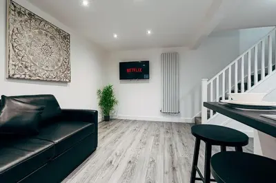 a living room with a black couch and a table at Park & Relax in 1bd Central Liverpool home in Liverpool