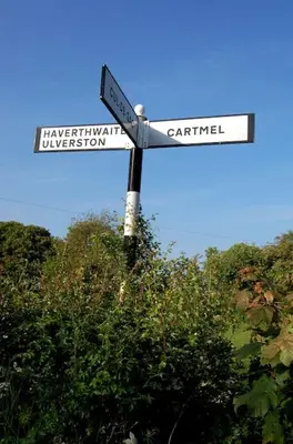 two street signs on a pole in front of trees at Cartmel Barn: Beckside Stables in Cartmel