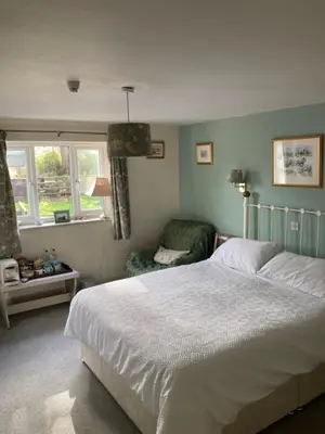 a bedroom with a bed and a chair and windows at Brandreth Barn in Burscough
