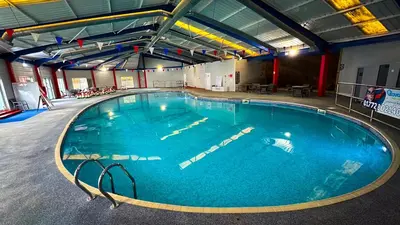 a large swimming pool with blue water in a building at Hobbit - Cosy Holiday Lodge with Pool in Longridge