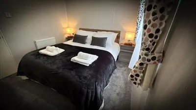 a bedroom with a bed with two towels on it at Hobbit - Cosy Holiday Lodge with Pool in Longridge