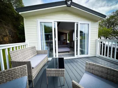 a patio with two chairs and a table on a deck at Hobbit - Cosy Holiday Lodge with Pool in Longridge