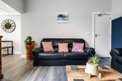 a black leather couch with pink pillows in a living room at Huge 5bedrooms/Ensuite/Liverpool/Ridley rd/Parking in Liverpool