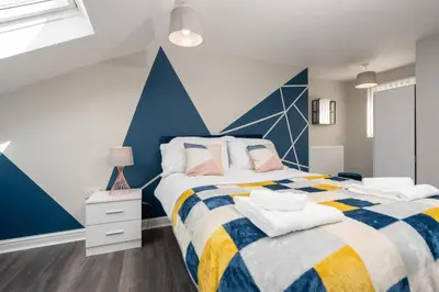 a bedroom with a bed with a blue accent wall at Huge 5bedrooms/Ensuite/Liverpool/Ridley rd/Parking in Liverpool