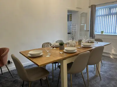 a dining room with a wooden table and chairs at Modernised 3-bedroom Blackburn townhouse sleeps 6 in Rishton