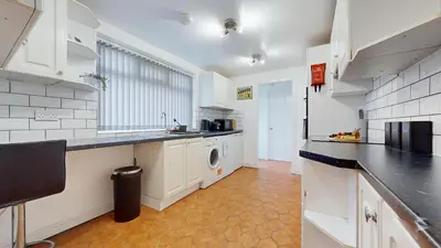 a large kitchen with white cabinets and a dishwasher at Modernised 3-bedroom Blackburn townhouse sleeps 6 in Rishton