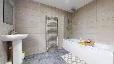 a bathroom with a sink and a tub and a toilet at Modernised 3-bedroom Blackburn townhouse sleeps 6 in Rishton