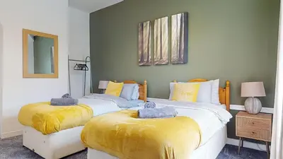 two beds in a room with yellow blankets at Modernised 3-bedroom Blackburn townhouse sleeps 6 in Rishton