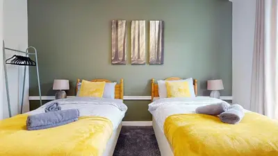 two beds in a room with yellow sheets at Modernised 3-bedroom Blackburn townhouse sleeps 6 in Rishton