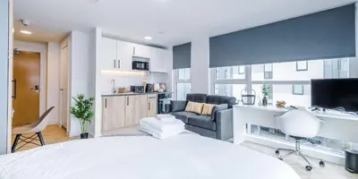 a bedroom with a white bed and a living room at City Studios, Preston in Preston
