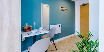 a room with a table and chairs and a blue wall at City Studios, Preston in Preston