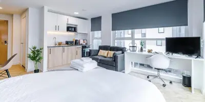 a bedroom with a white bed and a living room at City Studios, Preston in Preston