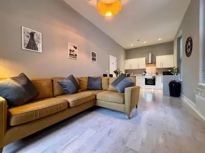a living room with a brown couch and a kitchen at Teds Apartments - Town Centre - Apt 1 in Blackpool