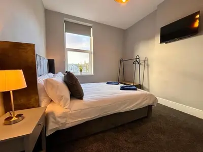 a bedroom with a bed with a lamp and a window at Teds Apartments - Town Centre - Apt 1 in Blackpool