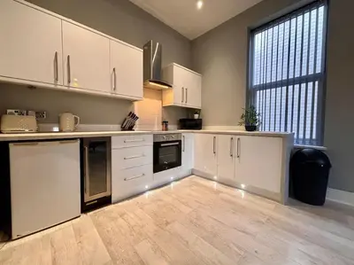 a kitchen with white cabinets and a large window at Teds Apartments - Town Centre - Apt 1 in Blackpool