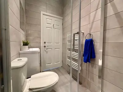 a bathroom with a toilet and a glass shower door at Teds Apartments - Town Centre - Apt 1 in Blackpool