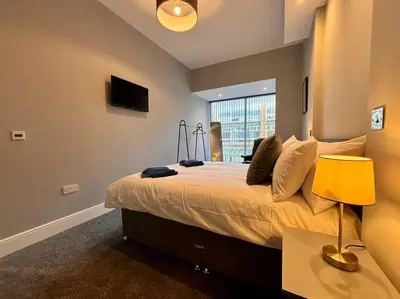 a bedroom with a large bed with a yellow lamp at Teds Apartments - Town Centre - Apt 2 in Blackpool