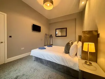 a bedroom with a bed with a lamp and a tv at Teds Apartments - Town Centre - Apt 2 in Blackpool